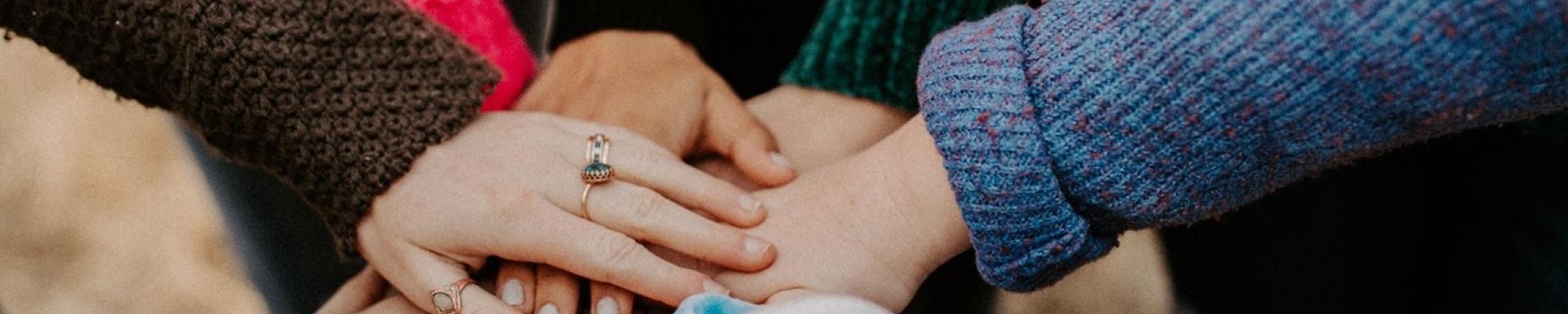 Diverse group with hands laid atop one another.